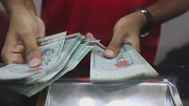 cashier-at-currency-exchange-counting-malaysia-ringgit-in-kuala-lumpur-malaysia-on-friday
