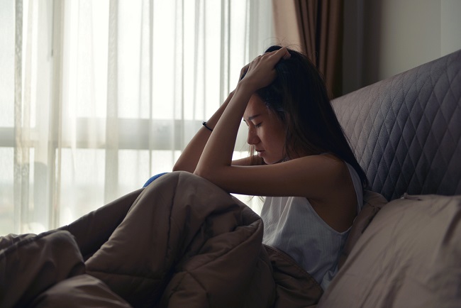 Asian,Woman,Suffering,From,Depression,Sitting,On,Bed