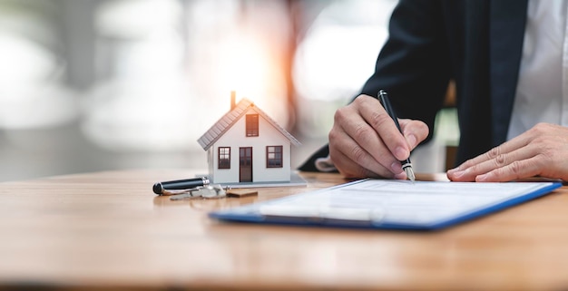 real-estate-concept-businessman-signs-contract-home-architectural-model_44344-4077