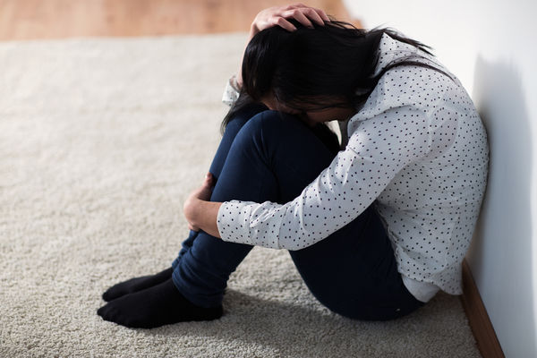 unhappy woman crying on floor at home